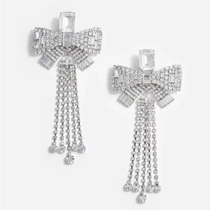 Elegant silver bow earrings with long rhinestone tassels on a clean white background