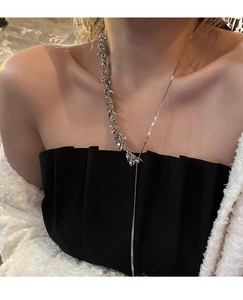 Makroaufnahme einer silbernen Ähren-Halskette mit asymmetrischer Schlangenkette am Hals