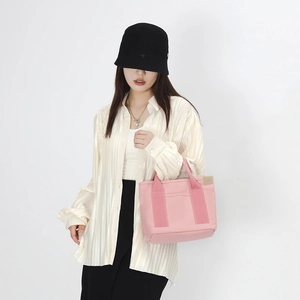Detailed view of pink canvas tote bag showing side pocket and woven handle on model