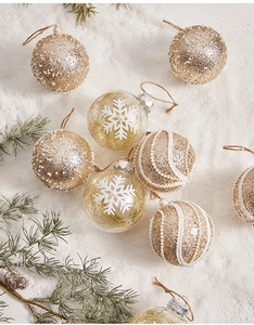 Detailed view of champagne gold and clear Christmas ornaments with snow accents and jute ropes