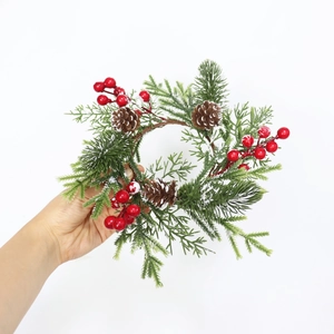 Handheld Christmas candle ring with red berries, pine needles and natural pine cones
