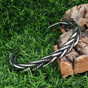 Detail of twisted cable cuff bracelet in polished silver stainless steel on wood