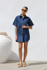 Outdoor shot of dark blue denim short sleeve shirt dress with buttons and large pockets