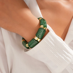 Detailed shot of dark green glitter resin beads and gold spacers on a stretch bracelet