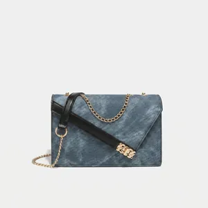 Detailed view of the dark wash denim handbag featuring gold push-lock and metal chain strap