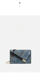 Detailed view of the dark wash denim handbag featuring gold push-lock and metal chain strap