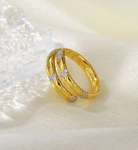 Macro detail of gold snake-patterned silver ring with zircon inlays on white silk