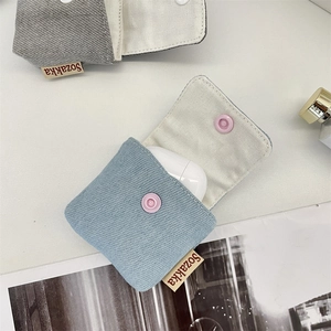 Close-up of canvas earphone pouches in light blue and grey with pink snap buttons