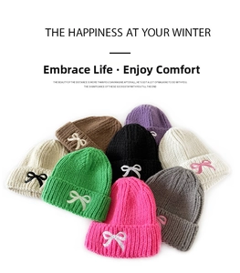 Detailed view of colorful knit beanies featuring contrasting embroidered bow accents