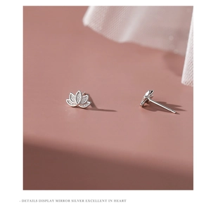 Macro view of minimalist S999 sterling silver lotus stud earrings on soft background
