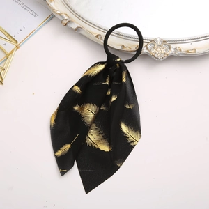 Detail of black chiffon hair scrunchie with gold feather print and ribbon design
