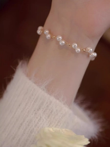 Detailed close-up of delicate double-layer woven pearl bracelet worn on a female wrist