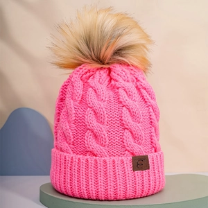 Close-up of rose pink cable knit beanie featuring thick texture and fluffy pompom detail