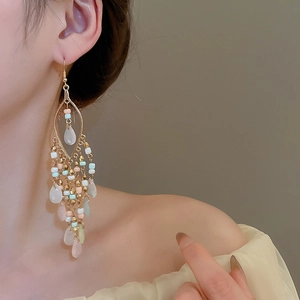 Detail von Perlen-Quasten-Ohrringen mit rosa und mintfarbenen Perlen an einem Model