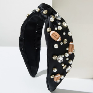 Detail of black knotted headband featuring rhinestones, pearls, and rugby-shaped charms