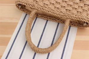 Detailed macro view of beige paper braid handbag showing intricate woven texture and handle