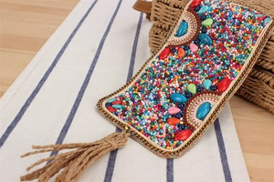 Détail d'une coque de téléphone bohème en perles colorées avec pompons en corde