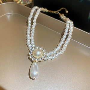 Détail d'un collier de perles à double rangée avec pendentif floral en strass