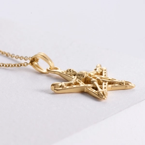 Macro view of 18K gold pentagram pendant with architectural hollow structure and satin finish