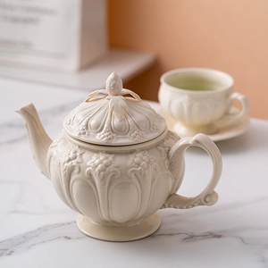 British vintage cream ceramic teapot with embossed floral patterns and matching teacup