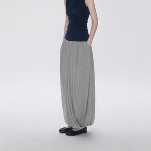 Detailed view of grey asymmetrical pleated skirt with flowing fabric and draped hemline