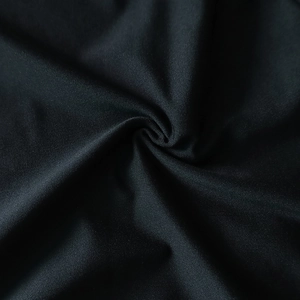 Détail de la texture du tissu noir de la robe avec plis en spirale et lumière douce