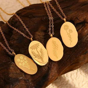 Detailed close-up of four gold oval pendants with floral embossing on dark wood background