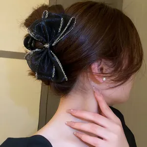 Pince à cheveux élégante avec nœud en résille noire et camélia en strass sur modèle