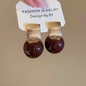 Detail of red resin drop earrings with brushed golden square studs for women