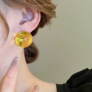 Gros plan d'une boucle d'oreille sphérique en résine ambre montrant la brillance et la transparence