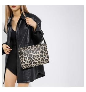 Dettaglio borsa shopper leopardata con finiture scure indossata da una modella