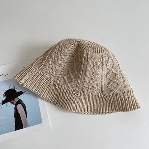 Detail shot of beige cable-knit bucket hat featuring thick cotton texture and ribbed brim