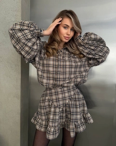 Detail shot of brown plaid lantern sleeves and pleated skirt hem showing woven texture