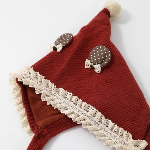 Cute red baby knit hat with lace trim and cream pom-pom for autumn and winter