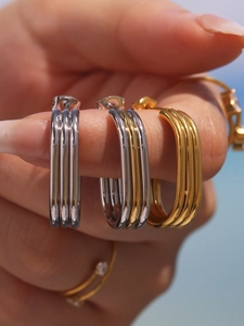Polished stainless steel triple hoop earrings in gold and silver finish on hand