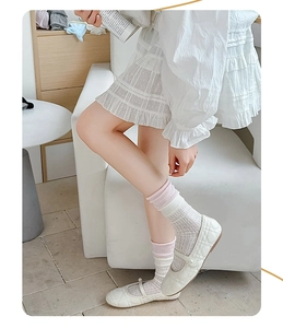 Close-up of white Mary Jane shoes with quilted texture and striped crew socks with pink trim