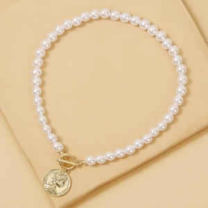 Detail of baroque pearl necklace with golden coin pendant and toggle clasp closure