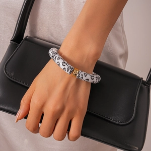 Detail of leopard print acrylic geometric bracelet with elegant gold metal ring accents