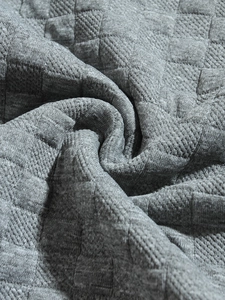 Close-up of gray knit fabric with quilted square texture and premium stitching detail