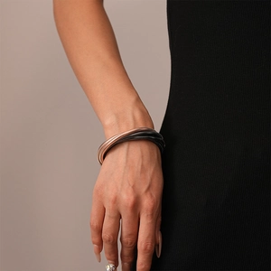 Detail eines mehrlagigen Schlangenknochen-Armbands in Roségold und Schwarz, Industriestil