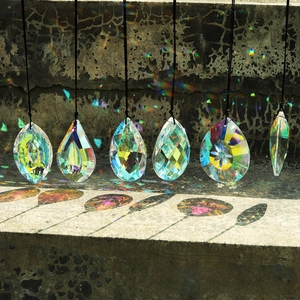 Detail of AB crystal pendants showing colorful rainbow reflections on a stone background