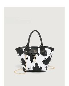 Detail of cow print bucket bag with golden chain strap and elegant pearl charm