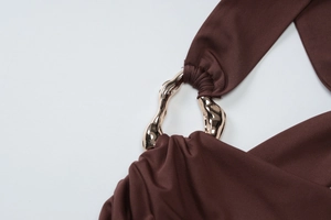 Close-up of brown bodycon dress showing metallic gold buckle and pleated fabric detail
