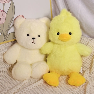 Cute teddy bear and duckling plush toys in soft fleece material on a warm knit blanket
