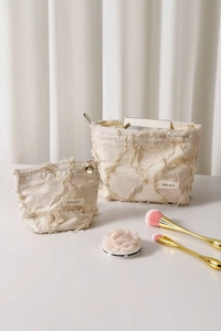 Detail of cream canvas toiletry bags with unique tassel texture and secure zipper closure