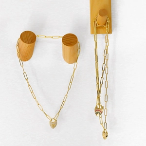 Détail de colliers chaîne trombone dorés avec pendentifs cœur en émail arc-en-ciel