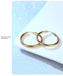 Macro shot of gold-plated stainless steel hollow hoop earrings on a white stand