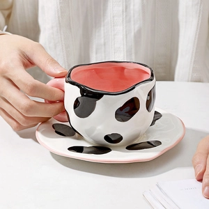 Irregular cow print ceramic coffee cup and saucer set with pink handle and artistic design