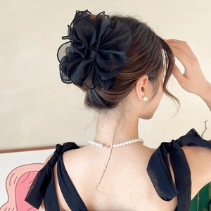 Détail de la pince à cheveux noeud en organza noir sur une coiffure élégante
