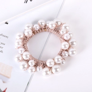 Detail of hand-woven beige elastic hair tie with assorted white pearls and shiny rhinestones